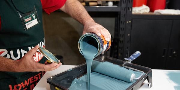 Bunnings Team Member pouring paint into paint tray.