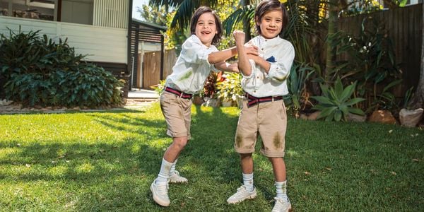 Two kids outside playing wearing grass stained clothes.