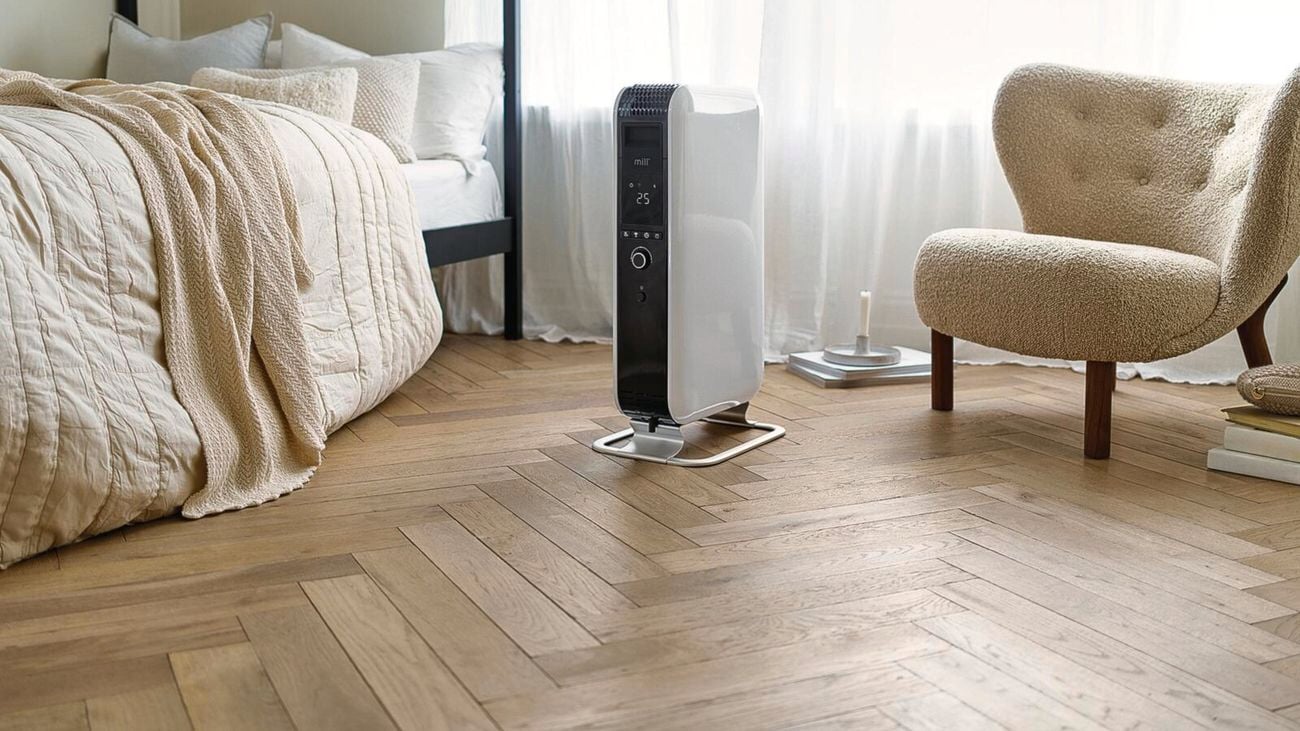 White radiator positioned in the middle of a bedroom behind sheer curtains