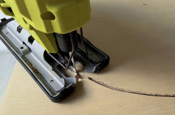 A jigsaw cutting a curved line in a piece of plywood