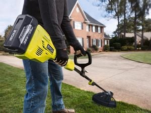A person using the Ryobi brushless line trimmer on the lawn edge