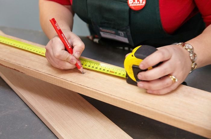 Person using tape measure to mark cuts to be made