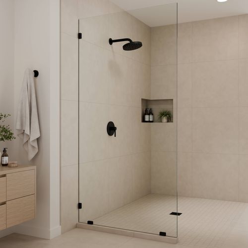 Walk-in shower with seamless clear glass panel, black hardware, and recessed shower niche.