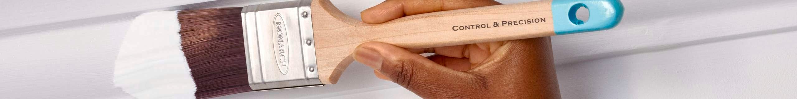 Paint brush applying white paint to trim