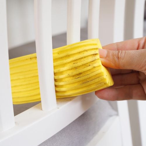A person cleaning a chair with the damp duster.