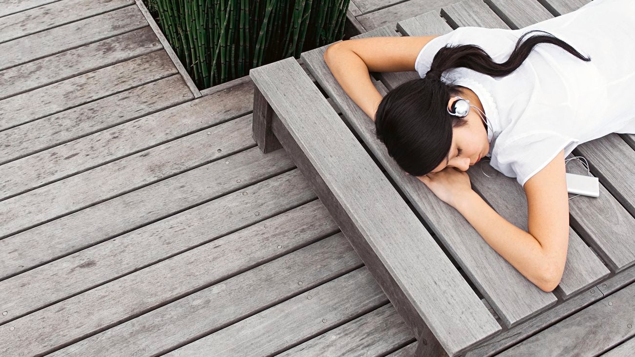 Person laying on a sunbed on a deck.