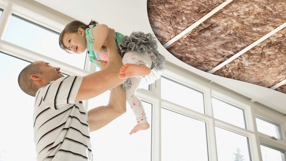 A man holding a baby and a ceiling with insulation wool.
