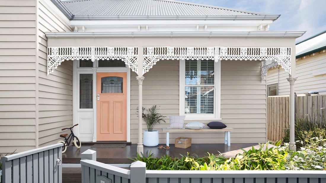 A white weatherboard cottage house with victorian latticework patio