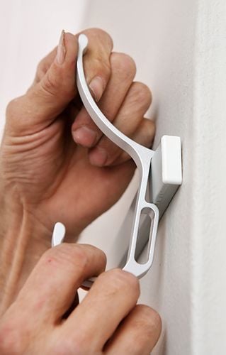 Close up of a hook being fitted over a wall mounted rail