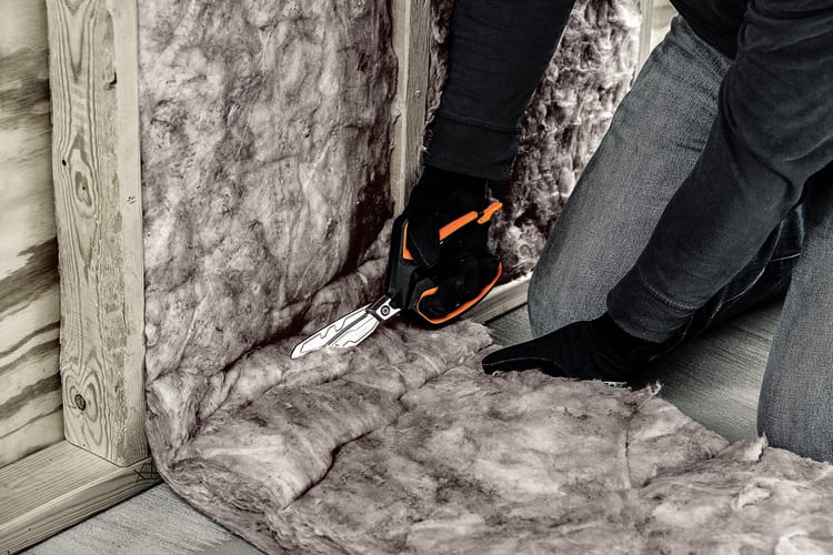 A tradesman using shears to cut through wall insulation