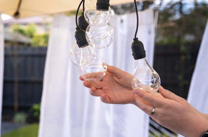 person holding onto outdoor festoon party lights