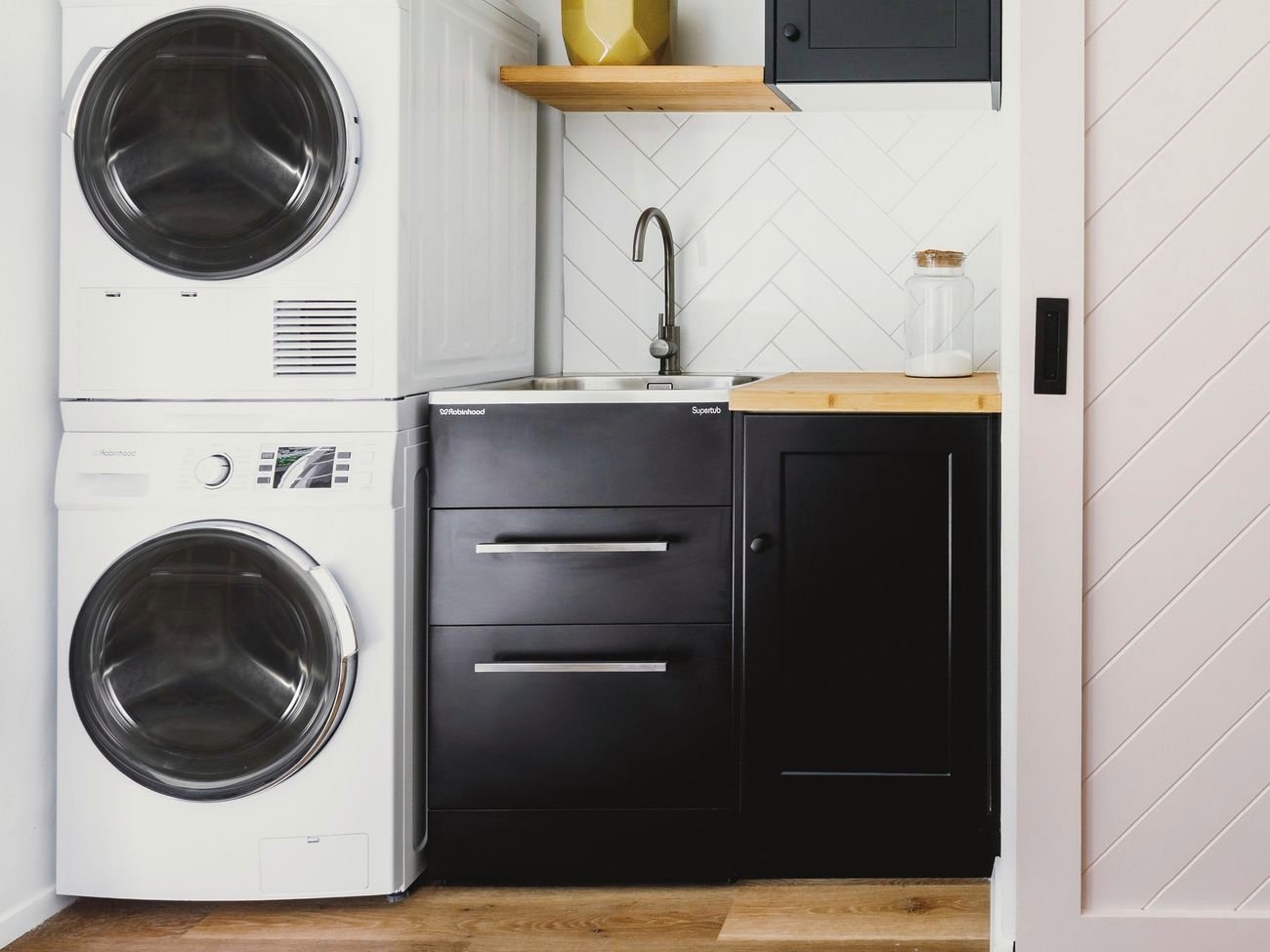 Washer and dryer stacked next to black cupboards