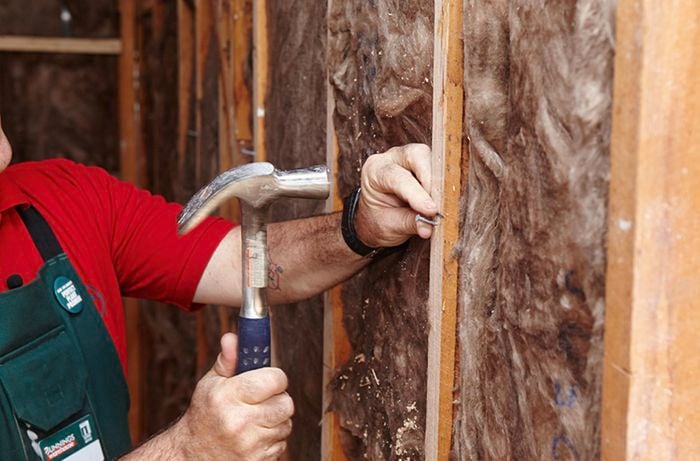 A nail being hammered into a wall beam as part of a ledge for villa board panels