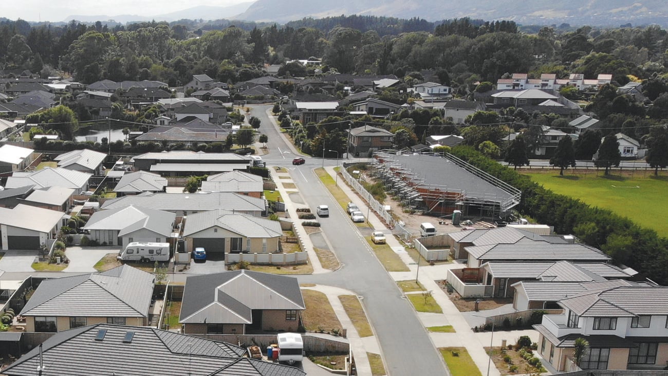 Aerial shot of a darkly painted home with grey fences, driveway and white painted windows