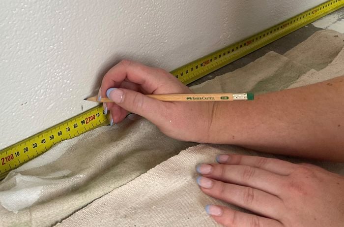 Person using a tape measure and pencil to mark width of stripes.