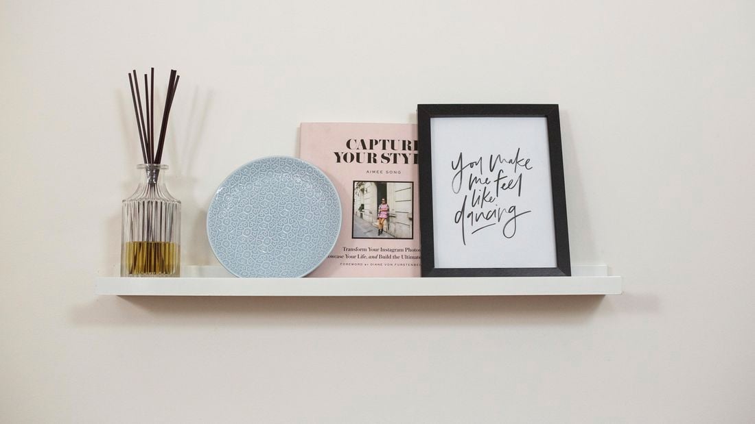 Wall-mounted shelf with a book, plate, vase and photo frame