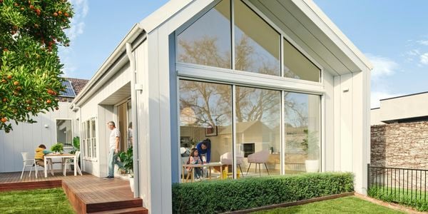House with family, large open windows, hedging and wrapped decking.