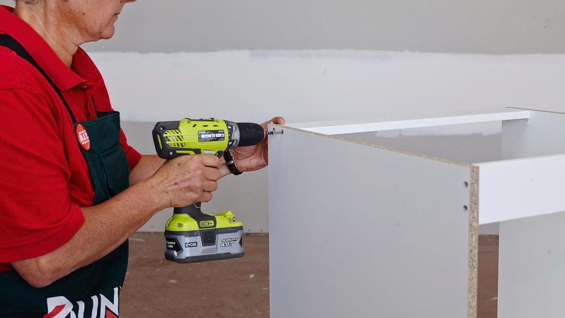 A person assembling cabinet panels with a cordless driver
