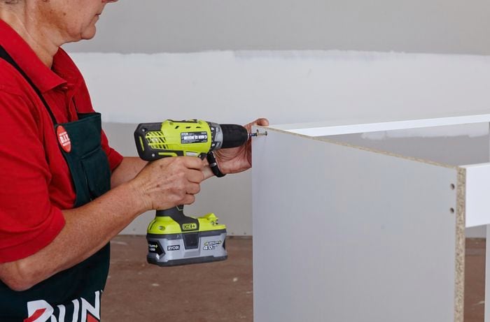 A Bunnings team member attaching top rails to an oven cabinet