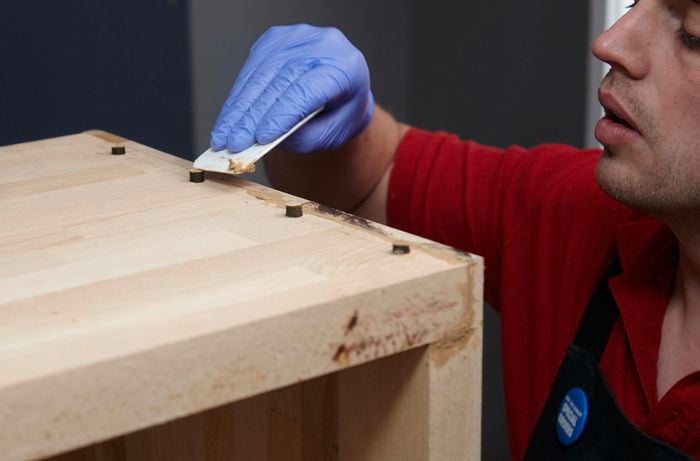 Person puttying up gaps in wood and sanding it off.