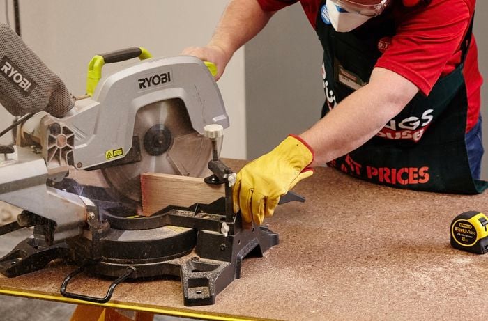 A person cutting timber using a drop saw