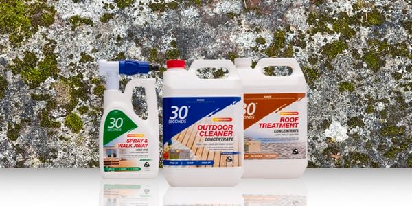 Three bottles of 30 second cleaning spray in front of a white wall with moss on it.
