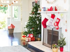 Living room decorated with a Christmas tree, bunting, fairy lights and stockings hanging over a fireplace