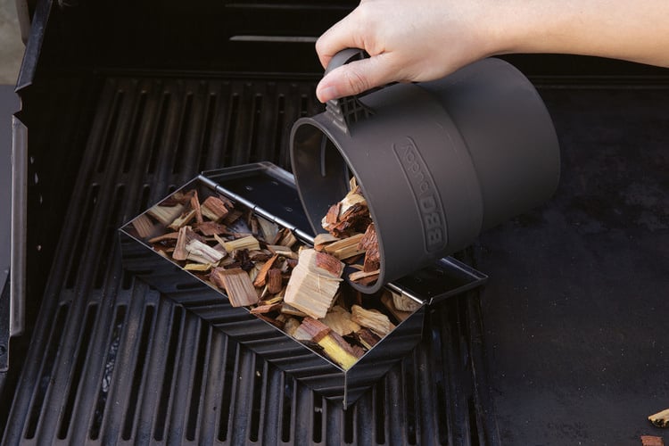 Person pouring wood chips into smoking tool