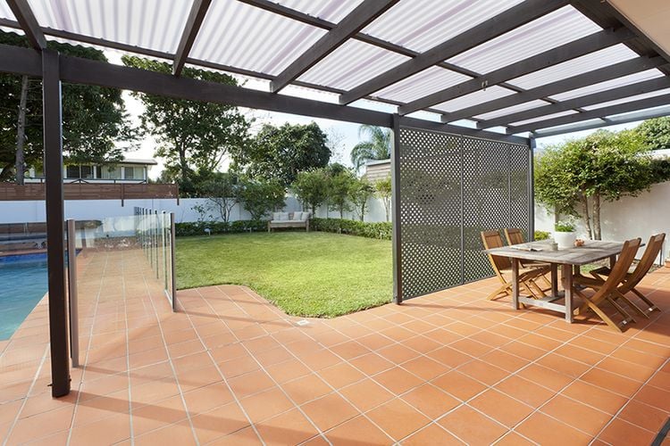 Backyard tiled area with dining table next to pool