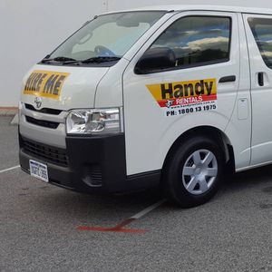 Two Handy Rental vehicles parked next to one another. There is a van on the left and a ute on the right.