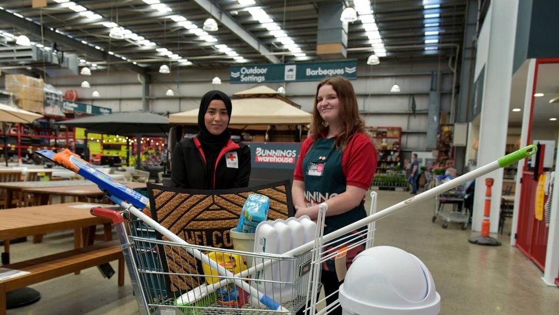 A Bunnings Team Member and a person in front of a trolley full of products in a Bunnings Store.