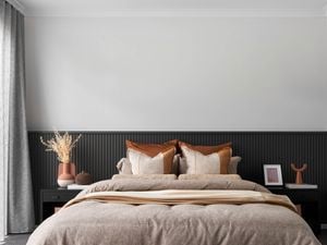 Modern bedroom with panelled walls, bedside tables and bed with earth coloured bedding, cushions and throw.