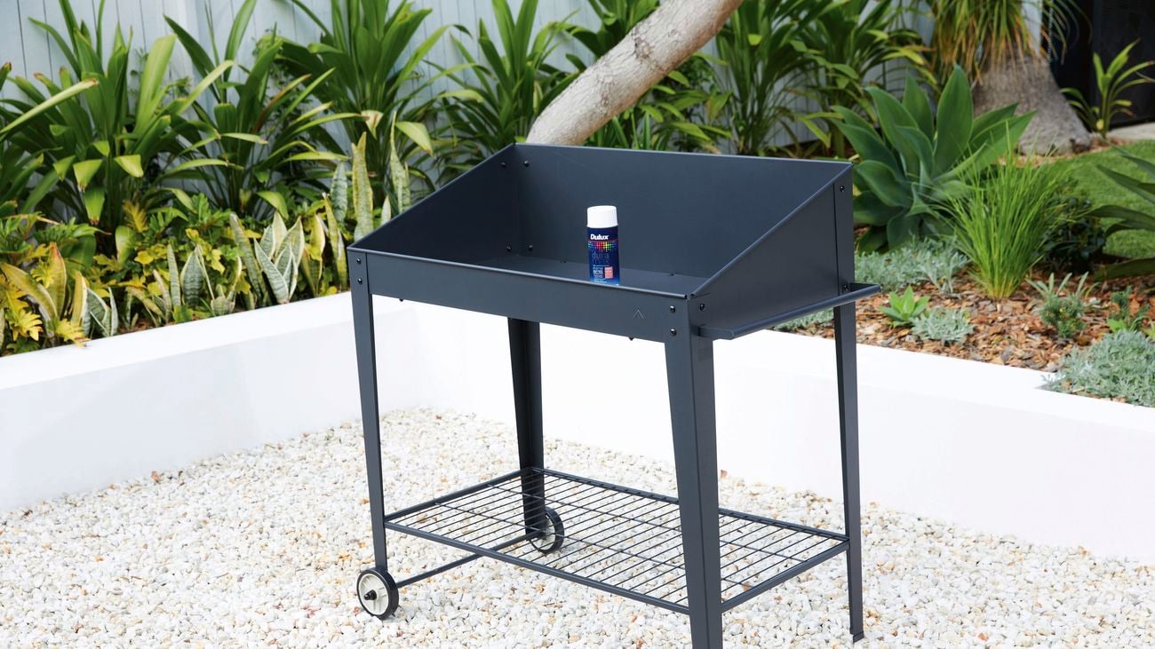 Shot of a black drinks trolley with black paint on top on a pebbled floor.