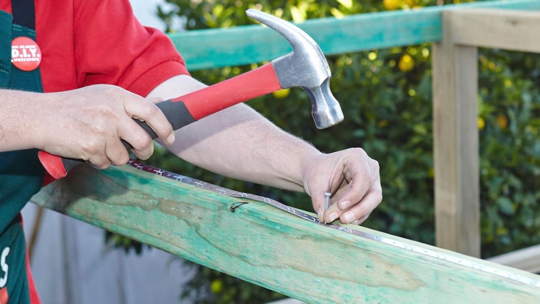 Fix strips being attached to a wooden frame with nails and a hammer
