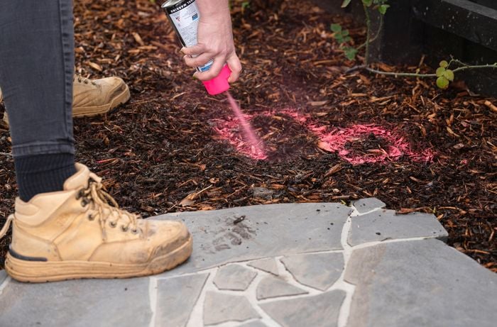 person spray painting on ground to dig holes