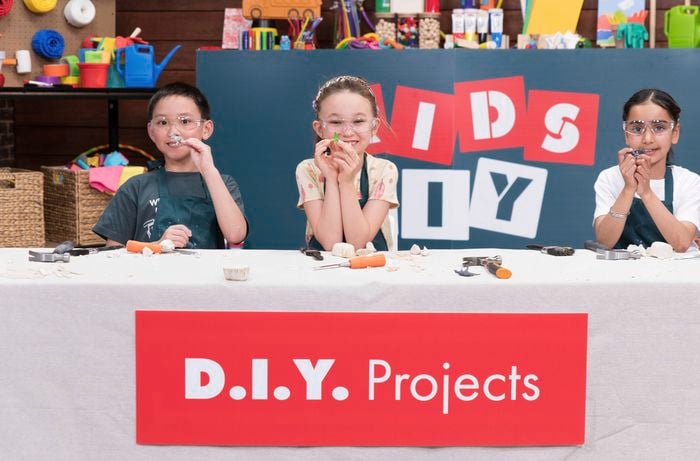  Three kids wearing safety goggles are proudly displaying their uncovered fossils at a Bunnings DIY workshop. 