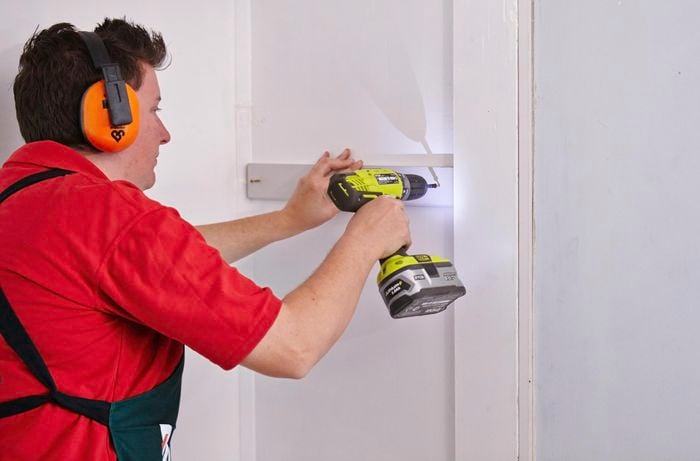 Person drilling cleat to wall.