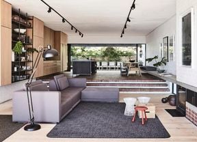 Living room with sunken lounge and long strips of pendant lighting.