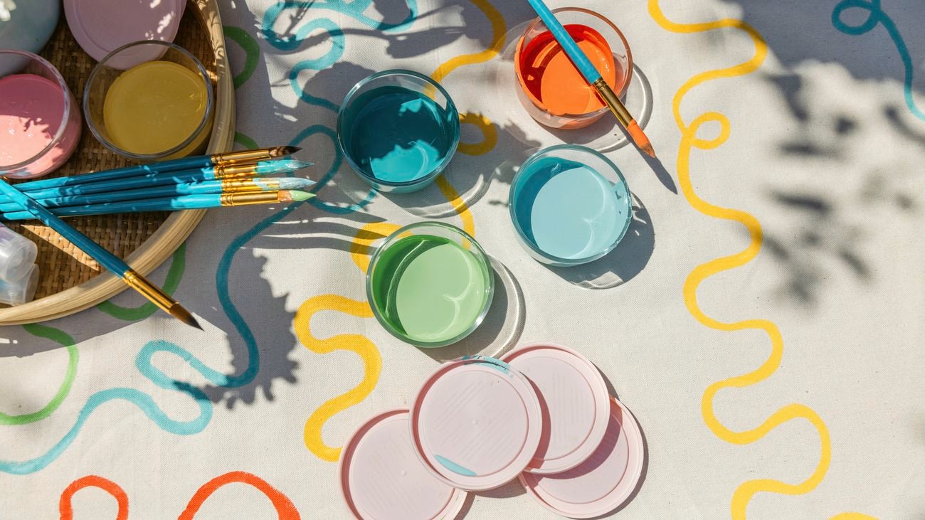 Various colours of paint in pots on a table.