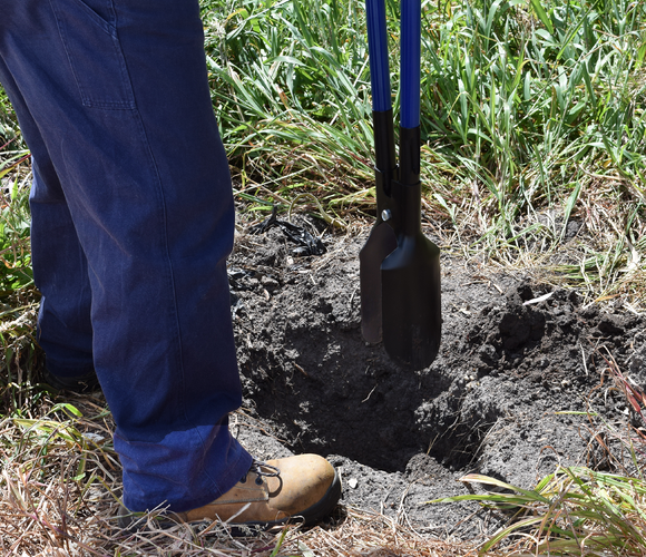 Person using a post hole pincer to dig a hole