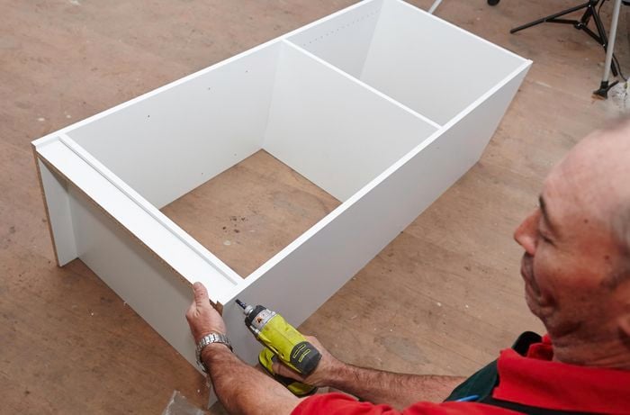 Person attaching side panel of wardrobe insert unit piece.