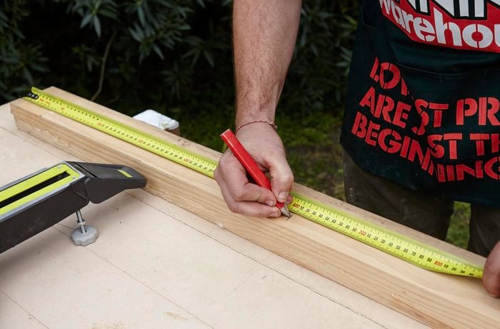 A length of timber being measured and marked for later cutting with a pencil and tape measure