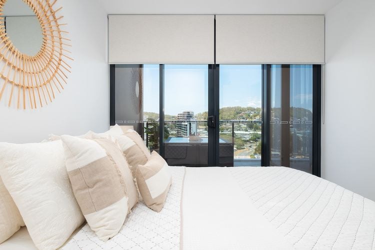 Bedroom in an apartment with white roller blinds partly closed