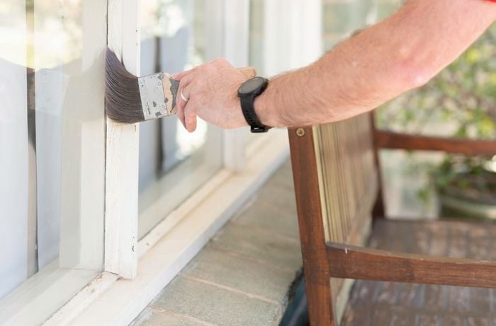 A persons hand brushes off the remaining dust to prepare the surface for painting.