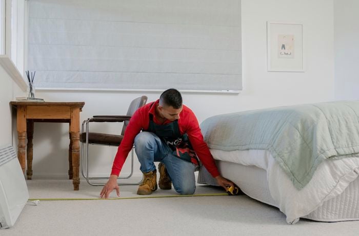 Team member measuring the room out with a measuring tape