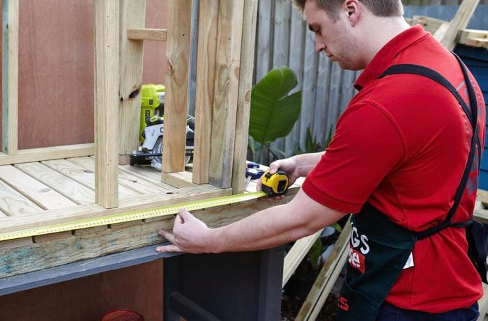 Person measuring timber frame.