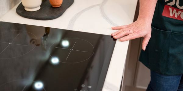 A person keeping his hand on an electric cooktop.