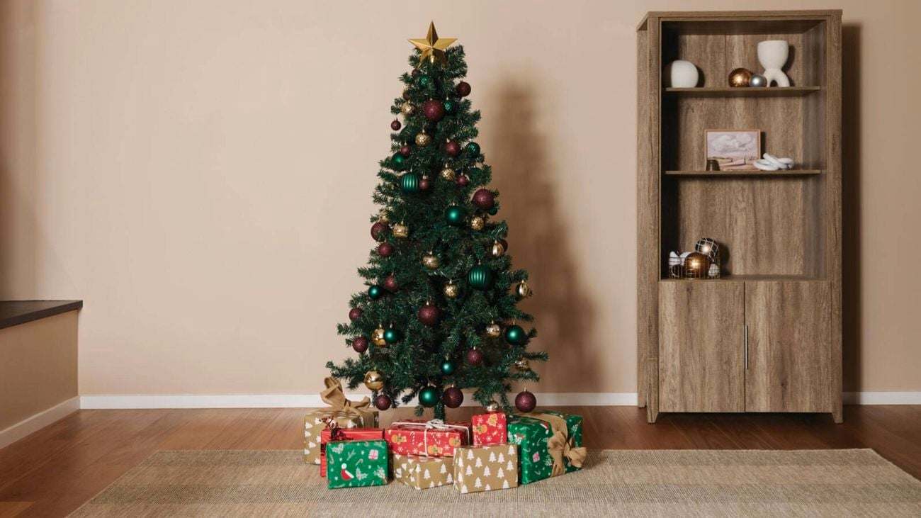 Green Xmas trees with Xmas lights, decorations and presents around the base.