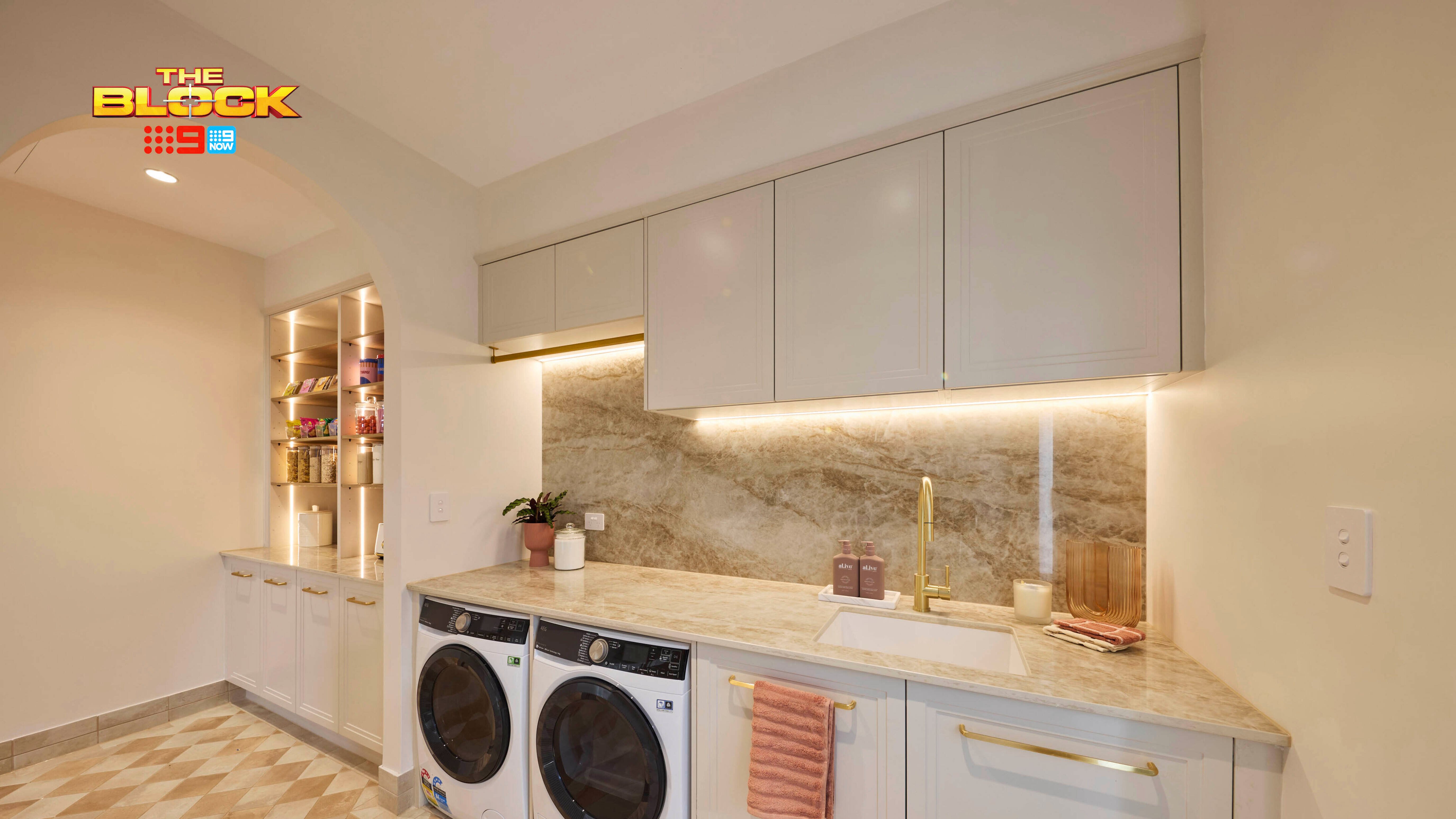 Laundry from The Block with marble splashback, under-cabinet lighting, washer and dryer, and built-in shelving.
