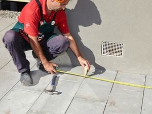 Person measuring and marking position on pavers